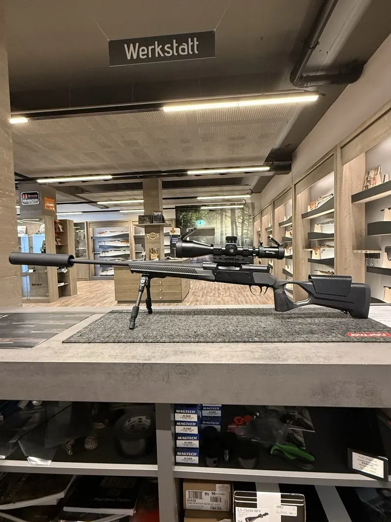 Gewehr mit Zielfernrohr und Schalldaempfer im Jagdshop-Verkaufsraum