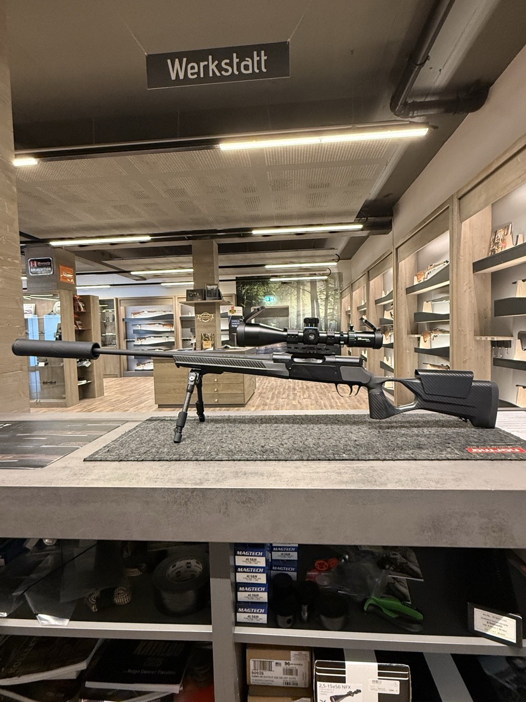 Gewehr mit Zielfernrohr und Schalldaempfer im Jagdshop-Verkaufsraum