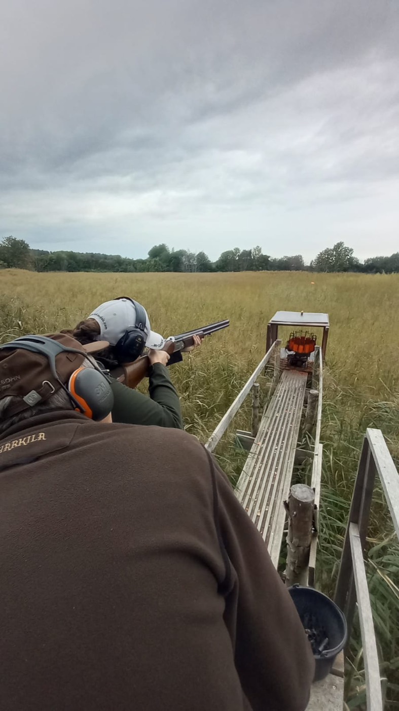 Jagdschueler beim Wurfscheibenschiessen mit Flinte und Gehoerschutz auf dem Schiessstand