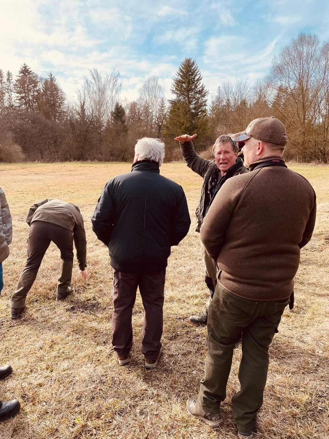Ausbilder erklaert Jagdschuelern auf der Wiese jagdliche Praxis im Revier der Jagdschule